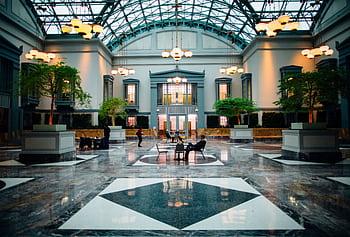 Spacious hotel lobby featuring modern architecture, luxurious design, and elegant lighting with minimal activity. HD wallpaper