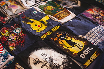 A vibrant assortment of graphic t-shirts featuring popular characters displayed in a market setting. HD wallpaper