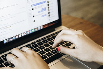 Close-up of hands typing on a laptop keyboard with a messaging app open on the screen. HD wallpaper
