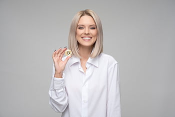 A cheerful woman displaying a bitcoin, embodying digital currency and modern finance. HD wallpaper