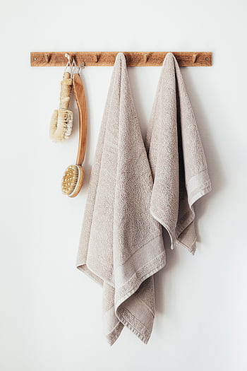Elegant bathroom decor featuring soft towels and eco-friendly brushes on a wooden hanger. HD phone wallpaper