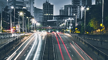 Dynamic night view of urban expressway with skyscrapers and light trails. HD wallpaper