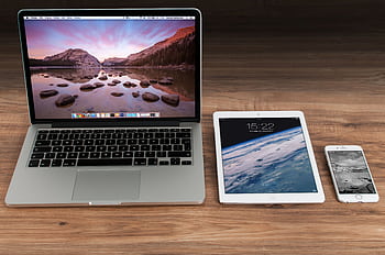 Modern workspace showcasing Apple laptop, tablet, and smart on a wooden desk. HD wallpaper