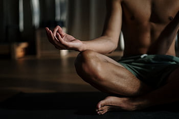 A shirtless man in a yoga studio meditating in the lotus position for relaxation and wellness. HD wallpaper