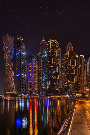 Explore the dazzling skyline of Dubai Marina at night, reflecting on calm waters. HD phone wallpaper