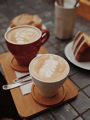 Delicious latte art accompanied by a slice of cake on a cafe table. HD phone wallpaper