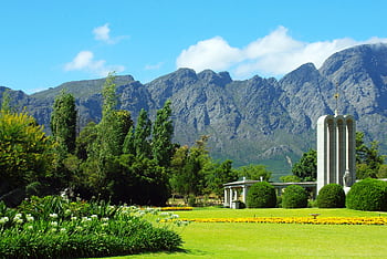 A scenic view of the Huguenot Monument in Franschhoek with lush gardens and mountain backdrop. HD wallpaper