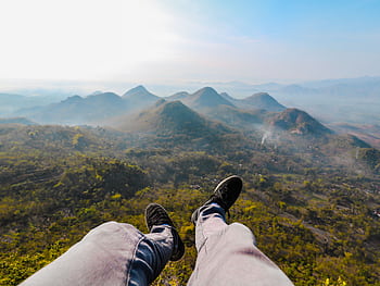 Feet dangling over the stunning landscape of Wonogiri Hills during sunrise, capturing the essence of Indonesian nature. HD wallpaper