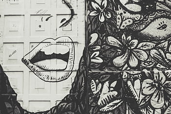Black and white street art featuring a face and floral patterns on a textured wall. HD wallpaper