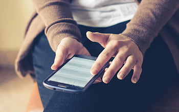 Close-up of adult using smart indoors, browsing web with focus on screen. HD wallpaper
