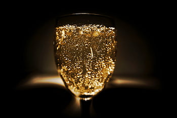 Elegant close-up of a champagne glass with bubbles against a dark background, perfect for celebrations. HD wallpaper