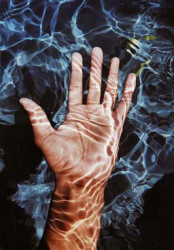 A hand submerged in clear blue water with captivating ripple effects, creating a soothing and artistic look. HD phone wallpaper