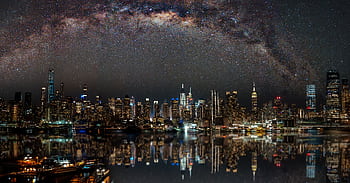 Nighttime view of New York City with stars reflecting on the water. HD wallpaper