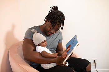 A loving father reads a book to his baby, fostering an affectionate bond. HD wallpaper