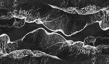 Stunning monochrome aerial shot of ocean waves crashing on the shore, creating abstract patterns. HD wallpaper