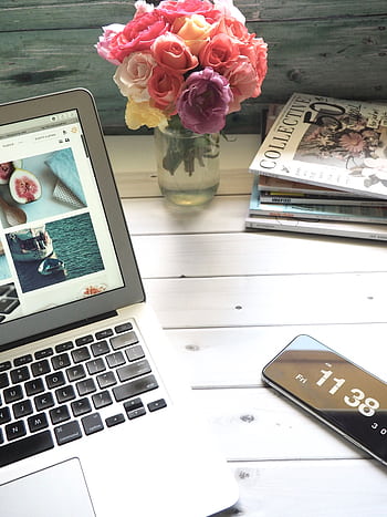 Elegant workspace featuring a laptop, smart, and fresh roses in a bright setting. HD phone wallpaper