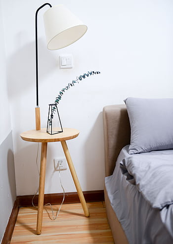 Modern minimalist bedroom with wooden nightstand, sleek lamp, and gray bedding set. HD phone wallpaper