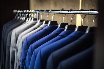 Close-up of neatly arranged suits in a wardrobe, showcasing fashion and organization. HD wallpaper
