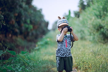 A young child engages in creative graphy outdoors, capturing nature’s beauty with a camera. HD wallpaper
