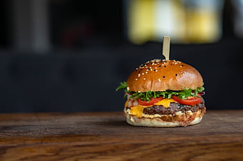 Mouth-watering cheeseburger with fresh ingredients on a wooden surface, perfect for food lovers. HD wallpaper