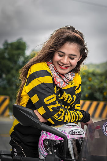 Young woman in bright attire smiling on motorcycle, enjoying the day. HD phone wallpaper