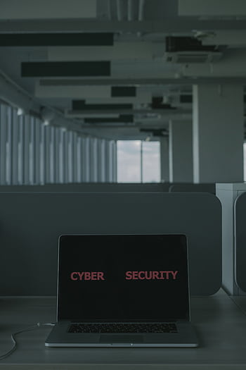 Laptop displaying 'Cyber Security' in a modern office setting, emphasizing tech and cybersecurity themes. HD phone wallpaper
