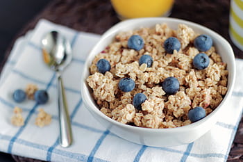 A delicious and healthy granola bowl topped with fresh blueberries, perfect for a nutritious breakfast. HD wallpaper
