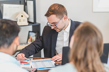 A real estate agent explains mortgage options to clients in an office setting. HD wallpaper