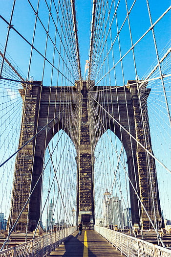 View of the iconic Brooklyn Bridge showcasing its architecture under a clear blue sky in New York City. HD phone wallpaper