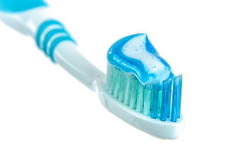 Detailed close-up of a toothbrush with vibrant blue toothpaste for dental hygiene. HD wallpaper