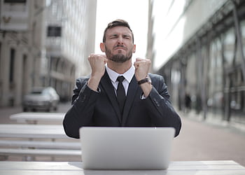 Confident businessman in Budapest celebrates success with a fist pump, reflecting a professional achievement. HD wallpaper