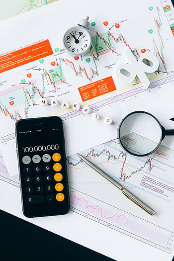 Flat lay of charts, calculator, and magnifying glass on office desk for market analysis. HD phone wallpaper