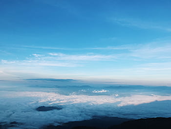A breathtaking aerial view of fluffy clouds beneath a clear blue sky with soft sunlight. HD wallpaper