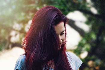 A thoughtful portrait of a young woman with vibrant red hair outdoors. HD wallpaper