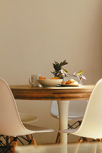 Cozy dining setup with wooden table, chairs, plant, and breakfast items. HD phone wallpaper