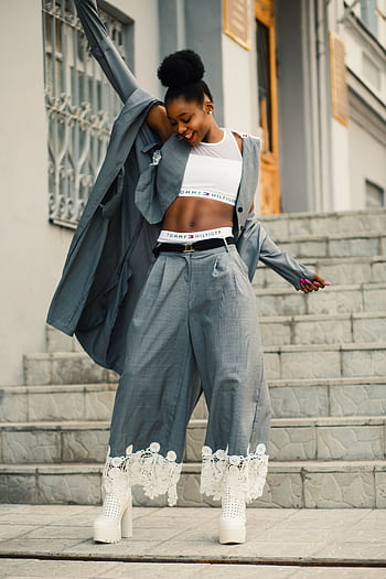 Confident young woman in chic outfit posing outdoors in a lively urban environment. HD phone wallpaper