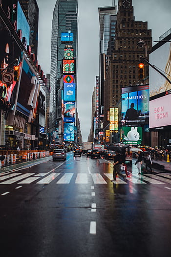 Bustling Times Square in New York City with illuminated billboards and pedestrians crossing. HD phone wallpaper