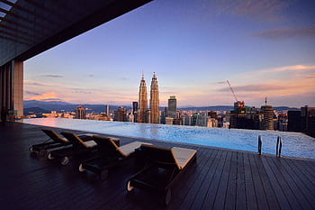Relax by a luxury infinity pool with stunning Kuala Lumpur skyline and Petronas Towers at twilight. HD wallpaper