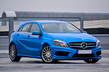 Elegant blue Mercedes-Benz hatchback parked outdoors with a modern architectural backdrop. HD wallpaper