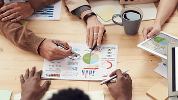 Colleagues discussing data and strategy in an office meeting. HD wallpaper
