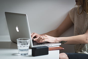 A young woman working remotely on her laptop at home, showcasing a modern lifestyle. HD wallpaper