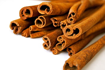 Aromatic cinnamon sticks displayed in a close-up view, capturing the texture and rich brown color. HD wallpaper