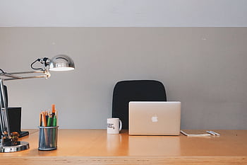 A tidy minimalist office setup featuring a laptop, desk lamp, and stationery. HD wallpaper