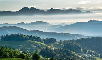 Breathtaking view of Slovenian mountains and valleys under soft morning mist, perfect for travel inspiration. HD wallpaper
