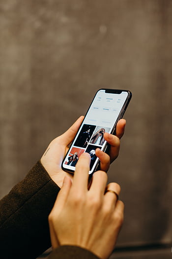 Close-up of hands using a smart to browse a gallery app, showcasing modern technology. HD phone wallpaper