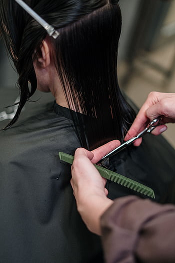 Close-up of a hairstylist cutting a woman's hair in a salon, showcasing precise techniques. HD phone wallpaper