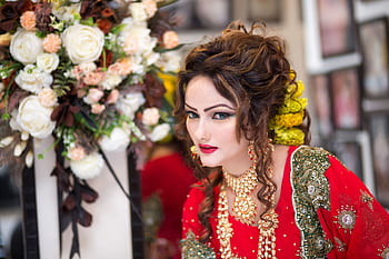 Beautiful South Asian bride in red traditional attire with floral bouquet, showcasing exquisite cultural style. HD wallpaper