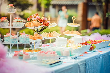 A vibrant outdoor buffet table showcasing an array of colorful pastries and fruits, perfect for parties. HD wallpaper
