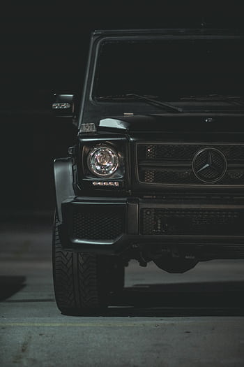 Close-up of a luxury black car's front, featuring a sleek design and emblem under nighttime lighting. HD phone wallpaper