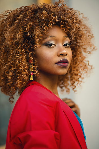 Striking portrait of a woman with curly hair, wearing a red jacket. HD phone wallpaper